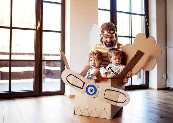 A father and toddler chidlren playing with carton plane indoors at home. - Photo, Image