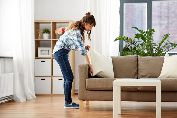 asian woman arranging sofa cushions at home - Foto, afbeelding