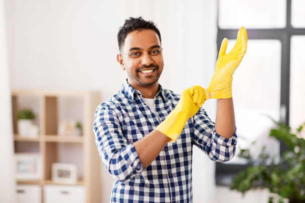 indian man putting protective rubber gloves on - 写真・画像