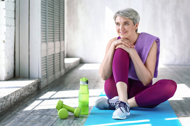 Sporty mature woman sitting on floor at home - Photo, image