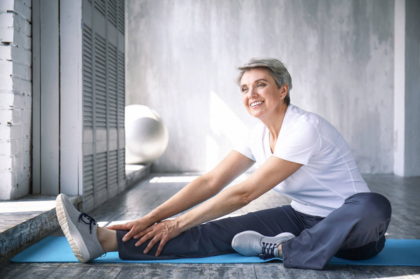 sportliche reife Frau trainiert zu Hause - Foto, Bild