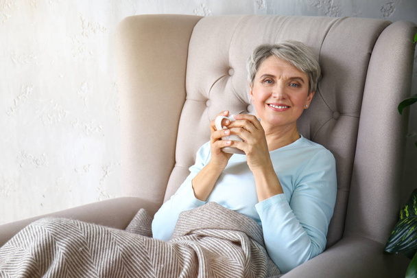 Portrait of beautiful mature woman drinking tea at home - Фото, изображение