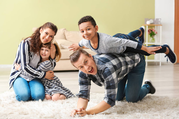 glückliches Paar spielt mit kleinen Adoptivkindern zu Hause - Foto, Bild