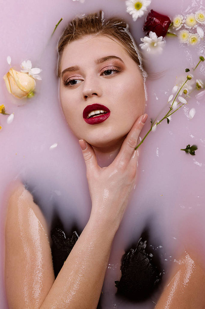 Femme blonde séduisante avec un maquillage parfait relaxant dans le bain avec
 - Photo, image