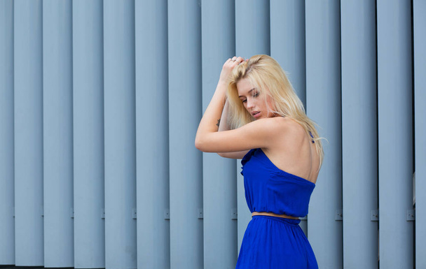 Glamorous ragazza bionda che indossa abito blu posa vicino shutt metallo
 - Foto, immagini