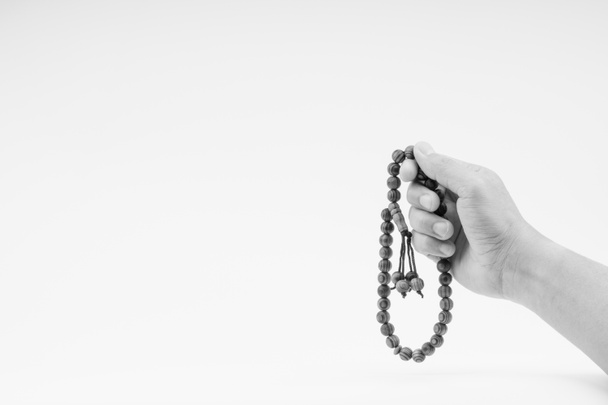 Hand hält einen muslimischen Rosenkranz Perlen oder Tasbih auf schwarz und weiß. Kopierraum und selektiver Fokus  - Foto, Bild