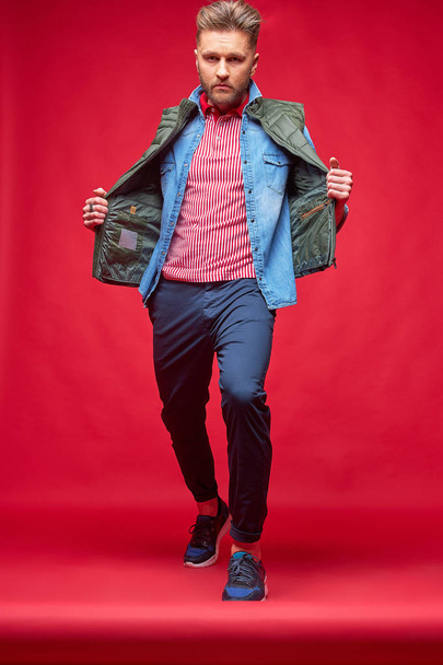 Male model posing in casual clothes. Fashion portrait, studio shot, red background - Fotografie, Obrázek
