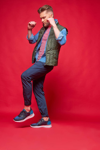 Male model posing in casual clothes. Fashion portrait, studio shot, red background - 写真・画像