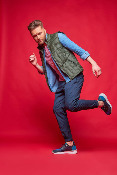 Male model posing in casual clothes. Fashion portrait, studio shot, red background - Foto, immagini