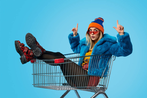 Weird female in shopping cart pointing up - Foto, afbeelding