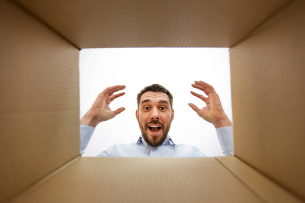 happy suprised man looking into open parcel box - Foto, Imagen