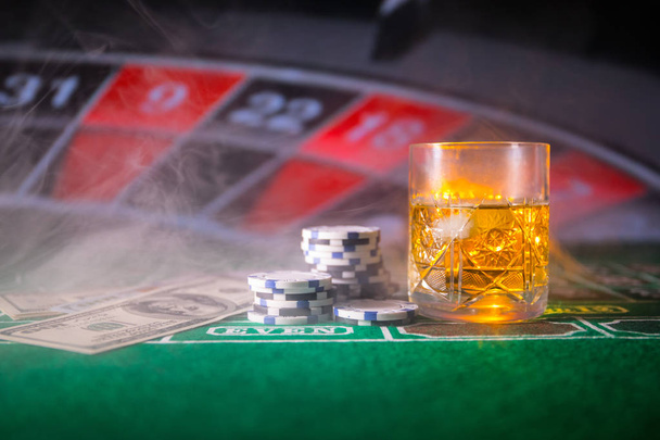 juego, fortuna, juego y concepto de entretenimiento - primer plano de fichas de casino y vaso de whisky en la mesa
 - Foto, Imagen