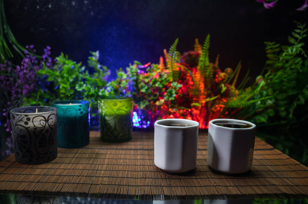 Çay konsepti. Japon çay töreni kültür doğu içecek. Gün batımında bambu yaprakları ile masada çaydanlık ve bardak - Fotoğraf, Görsel