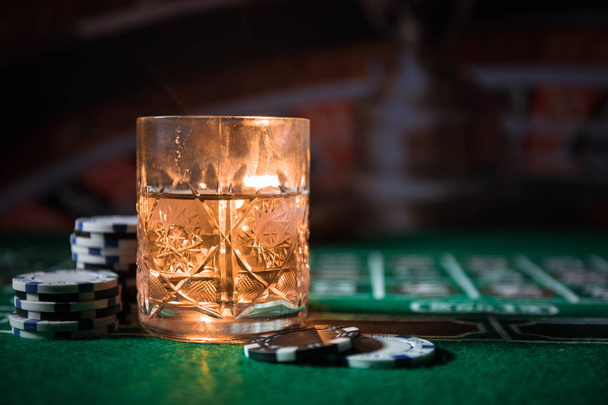 szerencsejáték, szerencse, játék- és szórakoztató koncepció - közelről kaszinó zseton és whisky-üveg asztal - Fotó, kép