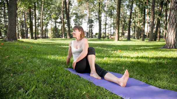 Foto de mulher sorridente de meia-idade praticando ioga asana. Persong meditando na natureza. Equilíbrio e harmonia de corpo e mente
 - Foto, Imagem