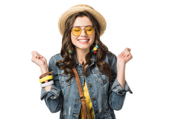 excitada chica boho en boater y gafas de sol sosteniendo puños con los ojos cerrados aislados en blanco
 - Foto, imagen