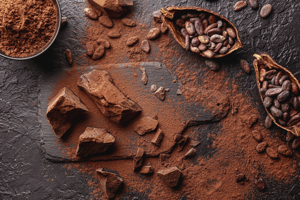 Composition with cocoa powder, beans and chocolate on table - Fotografie, Obrázek