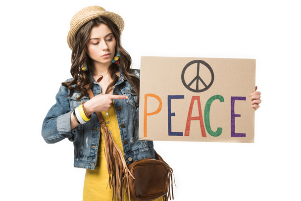 hippie girl in straw hat pointing with finger at placard with inscription isolated on white - Photo, Image