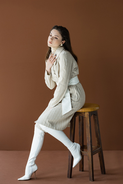 stylish woman sitting on wooden chair isolated on brown - Φωτογραφία, εικόνα
