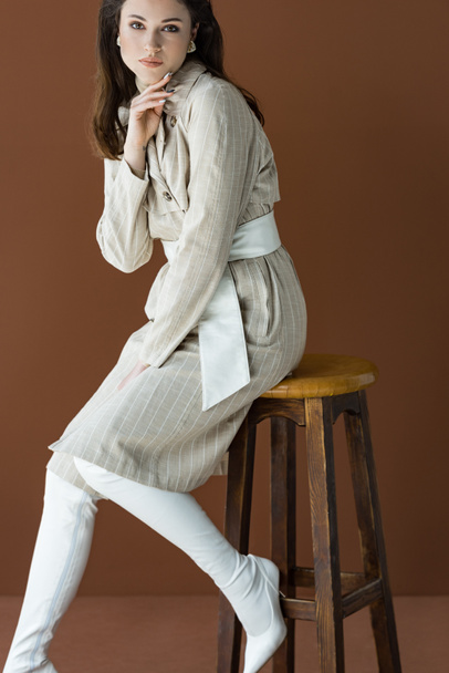 beautiful woman in stylish trench coat isolated on brown, looking at camera - Photo, Image