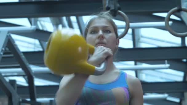 Girl in the gym, lifts metal weights and frowning with effort. - Imágenes, Vídeo