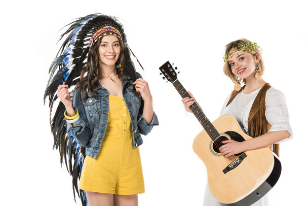 インドの頭飾りと白で隔離されたアコースティックギターを持つリースの2人のバイセクシャルヒッピーの女の子 - 写真・画像