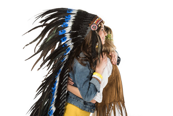 two bisexual hippie girls in indian headdress and wreath embracing isolated on white - Фото, зображення