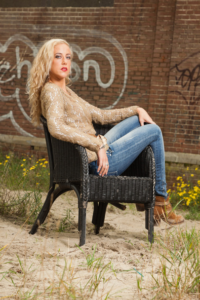 Pretty blonde fashion girl sitting in chair outdoor in urban env - Photo, Image