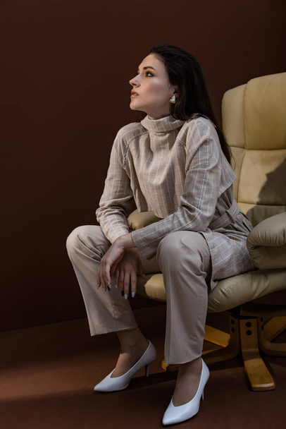 fashionable woman sitting on armchair ,looking away - Foto, Imagem