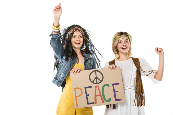 zwei bisexuelle Hippie-Mädchen in indischer Kopfbedeckung und Kranz mit Plakat mit Inschrift isoliert auf weiß - Foto, Bild