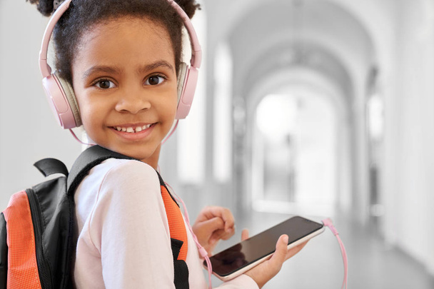 Child with school backpack and headphones posing. - Foto, afbeelding