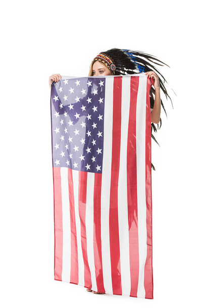 Вид в полный рост девушки в индийском головном уборе, держащей американский флаг, изолированный на белом
 - Фото, изображение