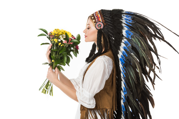 vista lateral de bonita chica boho en tocado indio sosteniendo flores aisladas en blanco
 - Foto, imagen