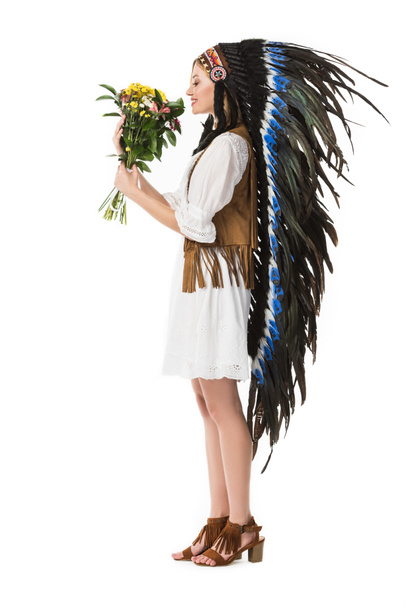 side view of smiling woman in indian headdress holding flowers isolated on white - Foto, immagini
