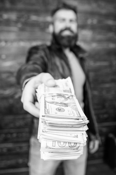 Richness and wellbeing. Mafia business. Man brutal bearded hipster wear leather jacket and hold cash money. Illegal profit and black cash. Guy mafia dealer with cash profit. Man give cash money bribe - Фото, изображение