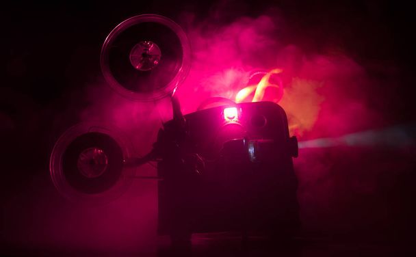 Stare zabytkowe projektor filmowy na ciemnym tle z mgłą i światłem. Koncepcja produkcji filmowej. - Zdjęcie, obraz