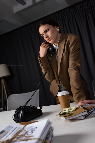 vista de ángulo bajo de la triste mujer de negocios con el teléfono en la mano hablando por teléfono, mirando hacia otro lado
 - Foto, imagen