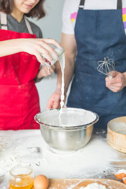 Baker adds flour to dough in an iron bowl on the table in the bakery - Foto, Imagen