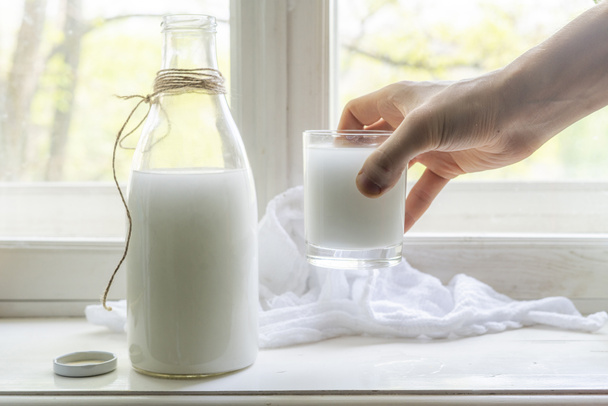 friss nyers tehéntej egy ablakpárkányon, egészséges reggeli a faluban, öntsük a tejet az üvegen - Fotó, kép