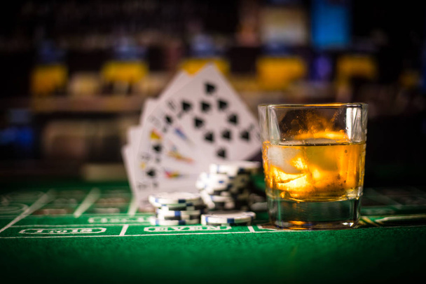 Glücksspiel, Vermögen, Spiel- und Unterhaltungskonzept - hautnah Casino-Chips und Whisky-Glas auf dem Tisch - Foto, Bild