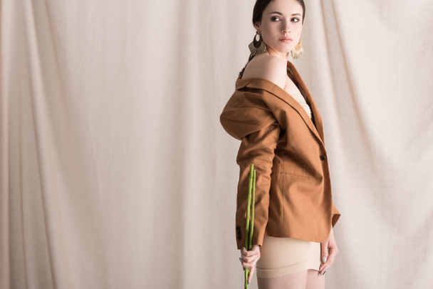 fashionable woman standing on curtain background, looking away - Foto, afbeelding