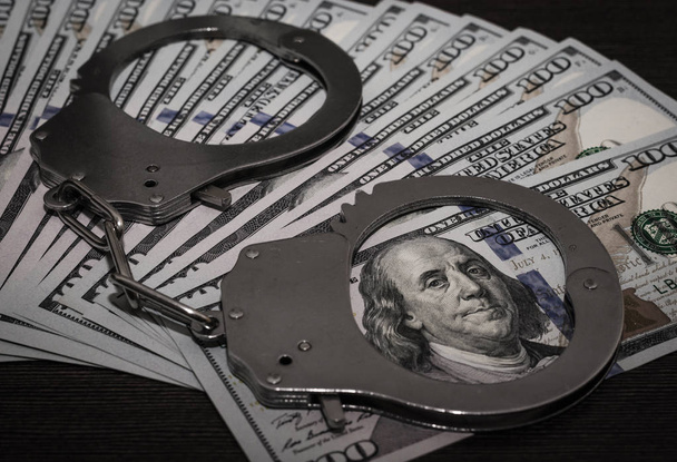 one hundred dollar bills and steel handcuffs close up - Фото, зображення