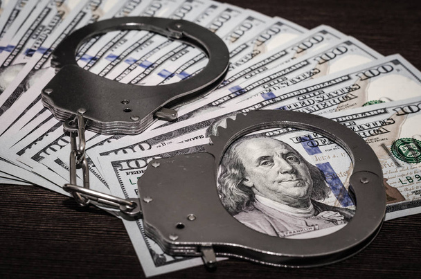 one hundred dollar bills and steel handcuffs close up - Zdjęcie, obraz