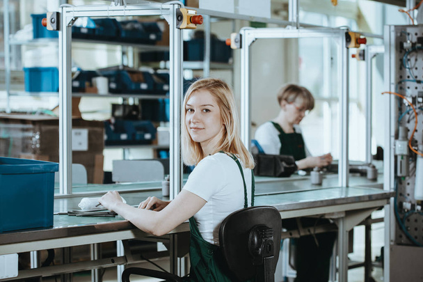 Pretty female student wearing green overall doing practical work at factory - Fotografie, Obrázek