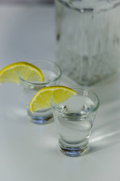 vodka in a glass with lemon - 写真・画像