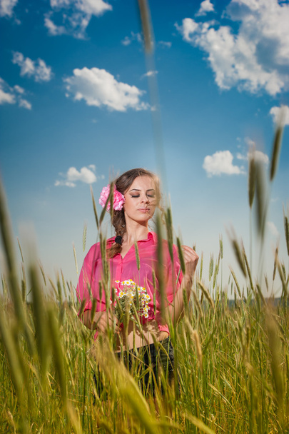 Young girl on golden wheat field.Portrait of beautiful blonde girl with wreath of wild flowers.Beautiful woman enjoying daisy field, pretty girl relaxing outdoor, harmony concept. - Photo, Image