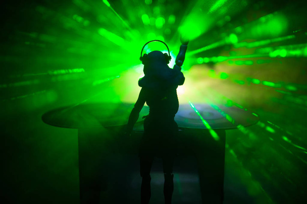 Concepto de club de DJ. Mujer mezclando DJ, y rascándose en un club nocturno. Silueta de niña en la cubierta de DJ, luces estroboscópicas y niebla en el fondo. Decoración creativa de obras de arte con juguete
. - Foto, Imagen