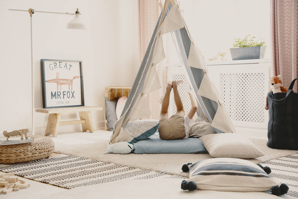 Real photo of a playroom interior with a tent, pillows and a kid having fun - Foto, Imagen
