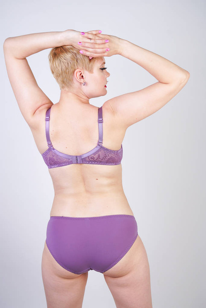 bastante curvilínea chica de pelo corto posando en lencería de encaje de moda púrpura en el estudio blanco solo
 - Foto, Imagen