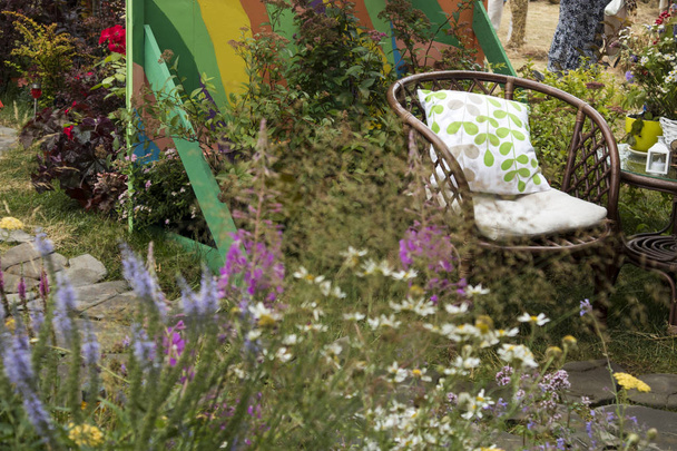Wiklinowe krzesła w ogrodzie przy stole z wazonem z roślinami. - Zdjęcie, obraz